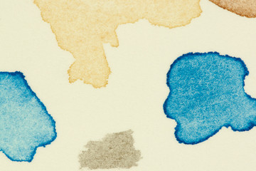 Test watercolor vibrant paint spots on thick aquarelle paper sheet, left as group of small drops and splash marks, showing artistic irregular formations of chaotic type