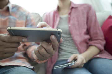 The couple are looking at a smart phone on the sofa