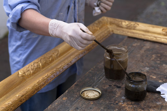 Frame-maker in workshop patinating Baroque wooden frame