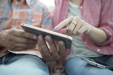 The couple are looking together smartphone on the sofa