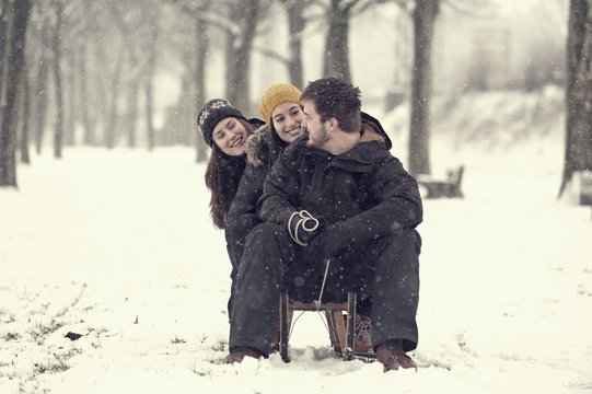 Three friends sitting on sledge in winter
