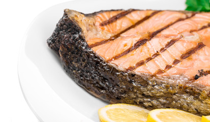 Grilled salmon steak with vegetables on plate.