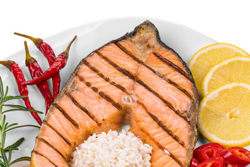 Grilled salmon steak with vegetables on plate.