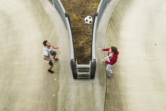 Two young men heading soccer ball over fence