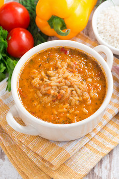 tomato soup with rice and vegetables on white wooden background