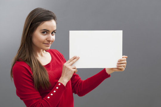 smiling young brunette wearing red holding a blank communication board with teasing news on