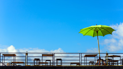 Chairs, table and umbrella on the balcony in blue sky