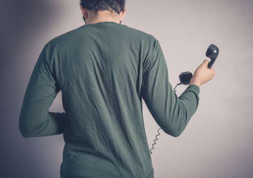 Rear view of man using rotary phone
