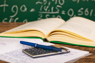 Back to school - blackboard with pencil-box and school equipment on table
