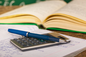 Back to school - blackboard with pencil-box and school equipment on table