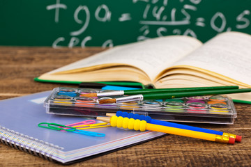 Back to school - blackboard with pencil-box and school equipment on table