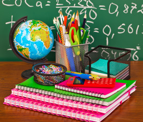 Back to school - blackboard with pencil-box and school equipment on table
