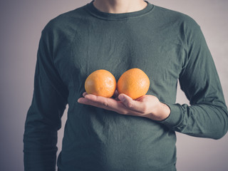 Young man holding two oranges © LoloStock