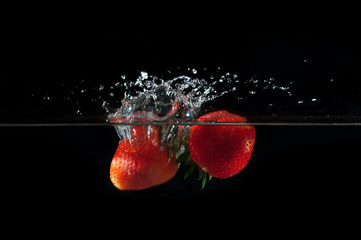 Strawberries splashing into water