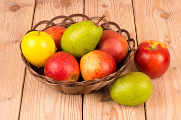 Naklejka na ściany i meble Apples and pears in the basket on the wooden background.