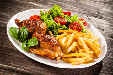 Grilled chicken legs with chips and vegetables 
