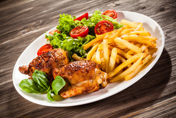 Grilled chicken legs with chips and vegetables 