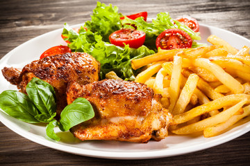 Grilled chicken legs with chips and vegetables 