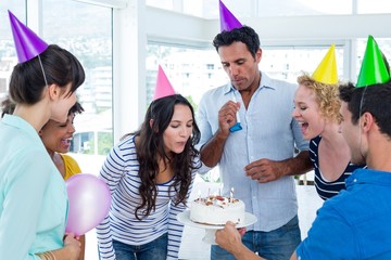 Businesswoman blowing candles on her birthday cake