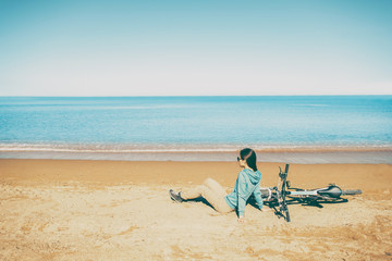 Fototapeta na wymiar Woman resting with bicycle on beach