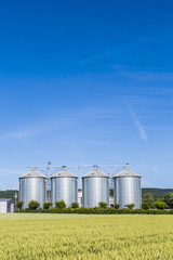 four silver silos in field under bright sky