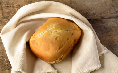 Loaf of bread on the linen napkin,   wooden background