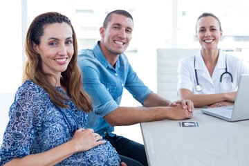 Obraz premium Doctor and future parents smiling at camera