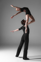 two young modern ballet dancers on gray studio background 