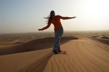 Fototapeta na wymiar Young woman steps on sand dune in Rub 'al Khali, United Arab Emi