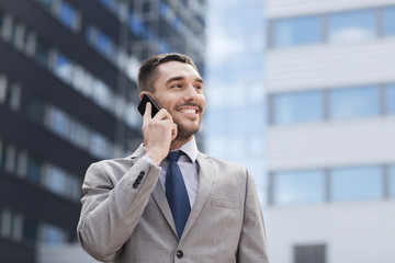 smiling businessman with smartphone outdoors