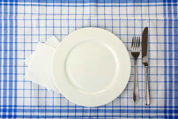 White plate, knife and fork on blue napkin