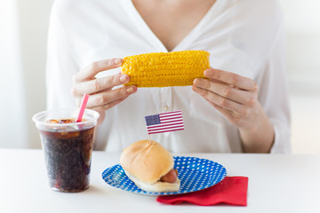 woman hands holding corn with hot dog and cola