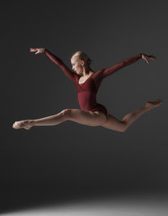 Fototapeta na wymiar Young beautiful modern style dancer jumping on a studio