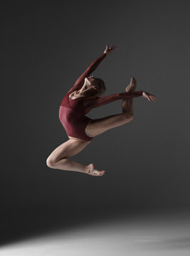 Young beautiful modern style dancer jumping on a studio