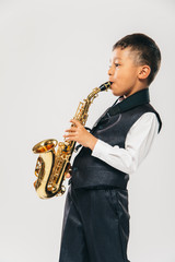 six years old boy plays saxophone at studio