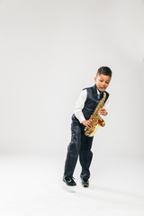 six years old boy plays saxophone at studio