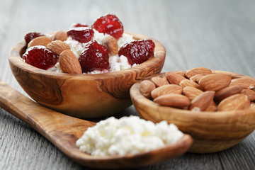 cottage cheese with preserved strawberry in wood bowl on oak