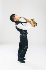 six years old boy plays saxophone at studio