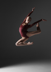 Fototapeta premium Young beautiful modern style dancer jumping on a studio