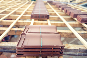 Roof under construction with stacks of brown roof tiles © aboutmomentsimages