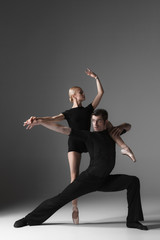 two young modern ballet dancers on gray studio background 