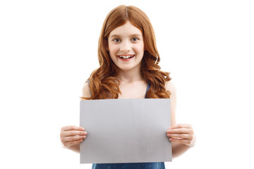 Fototapeta premium Positive little girl holding sheet of paper 