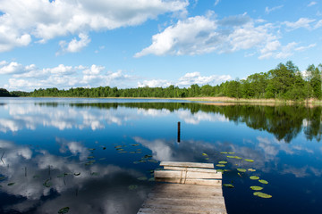 White clouds on the blue sky over blue lake with boats and board