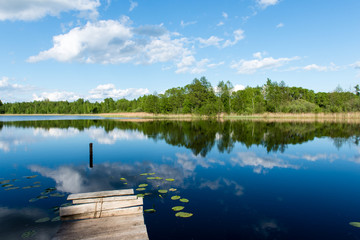 Naklejka na ściany i meble White clouds on the blue sky over blue lake with boats and board