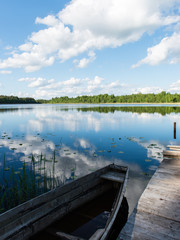 White clouds on the blue sky over blue lake with boats and board