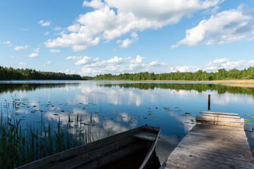 White clouds on the blue sky over blue lake with boats and board