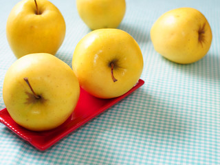 Still life with yellow apples on checkered table cloth