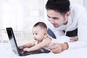 Curious baby typing on laptop with dad