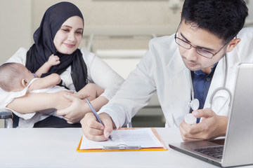 Doctor make prescription to mother and baby