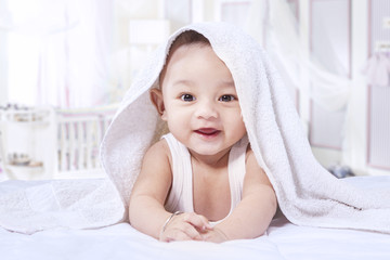 Fototapeta na wymiar Happy little baby smiling in the bedroom